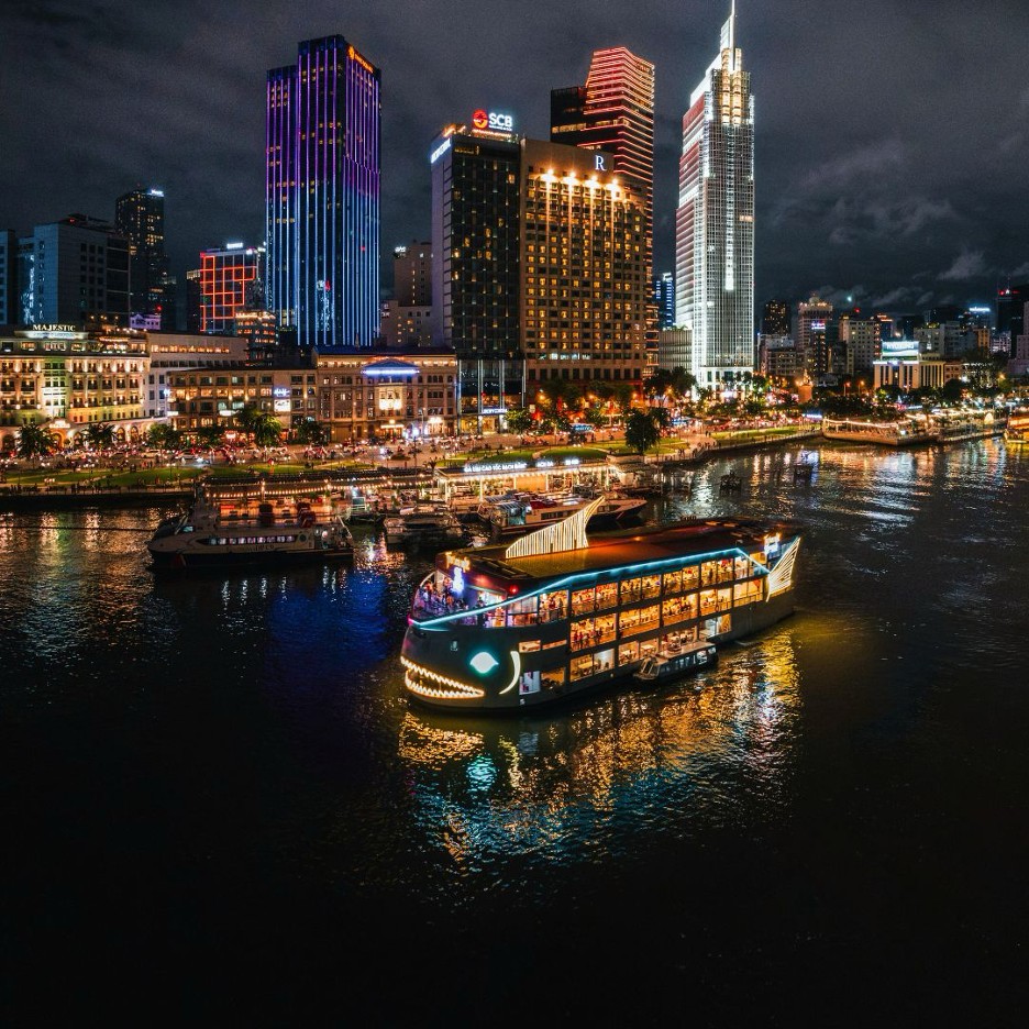 Ho Chi Minh City skyline at night from the Saigon River, illuminated cruise boat and skyscrapers