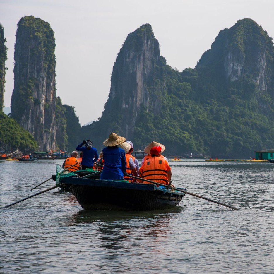 Traditional wooden boat with tourists among Ha Long Bay limestone karsts