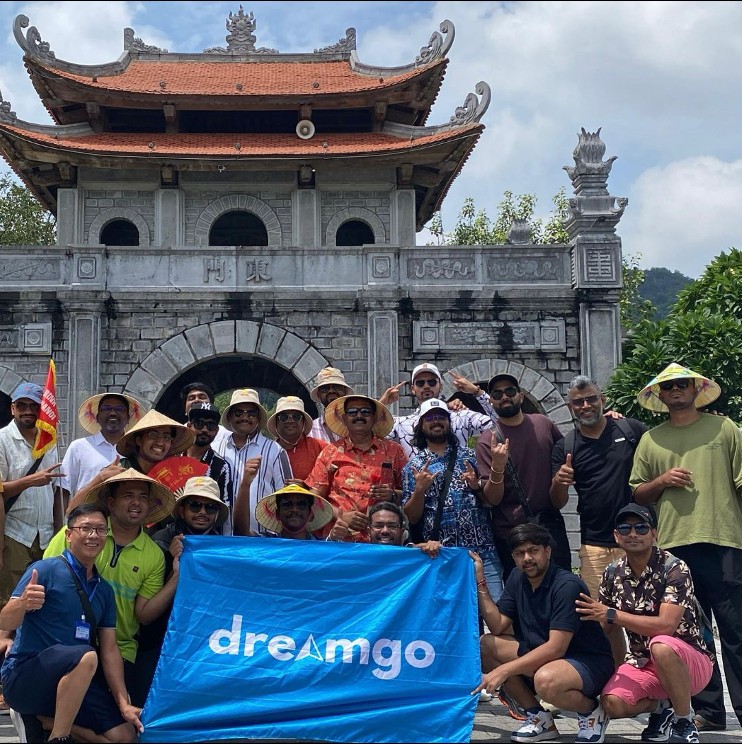 Dream Go group with branded banner at a historic Vietnamese stone gate